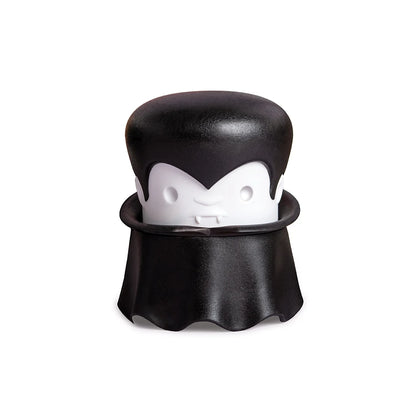 A cartoon vampire with a cape and fangs holds an OTOTO Gracula garlic crusher.